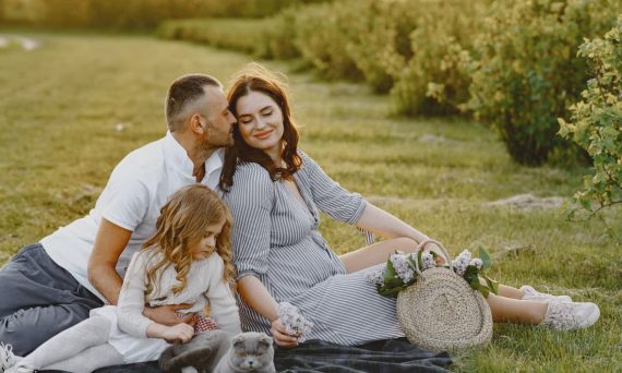 Family enjoying a joyful picnic in a sunny field with their pet cat, capturing a serene and loving moment.